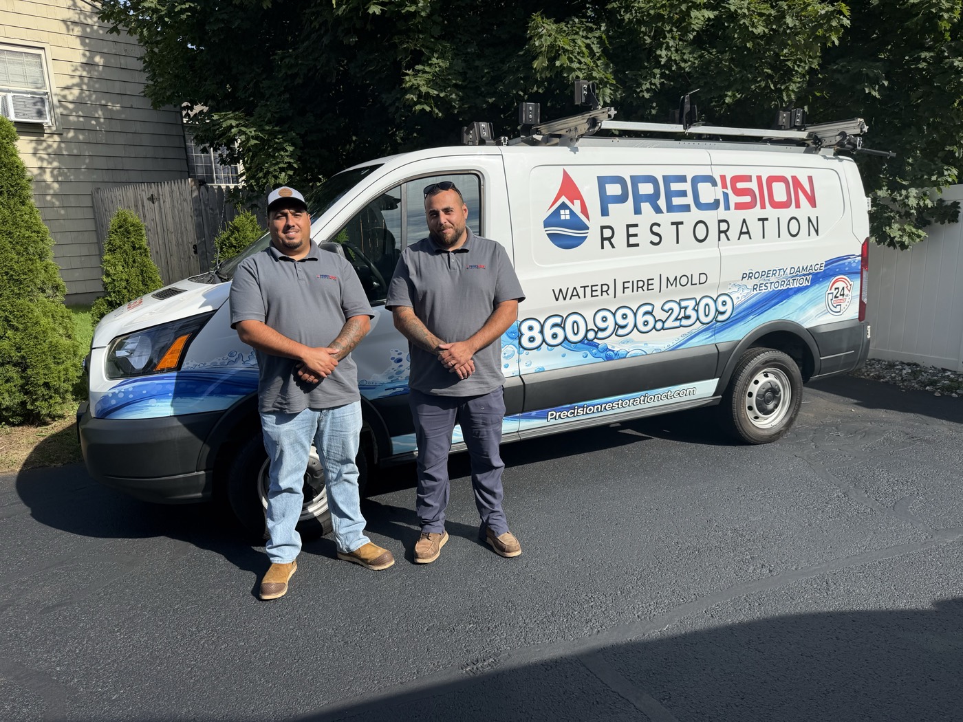 Sam and Steve of Precision Restoration CT standing in front of their branded restoration van