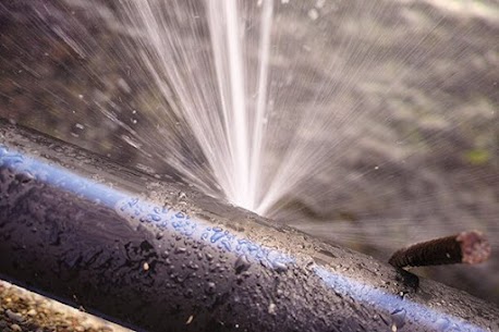 Water spraying under pressure from a split in a pipe
